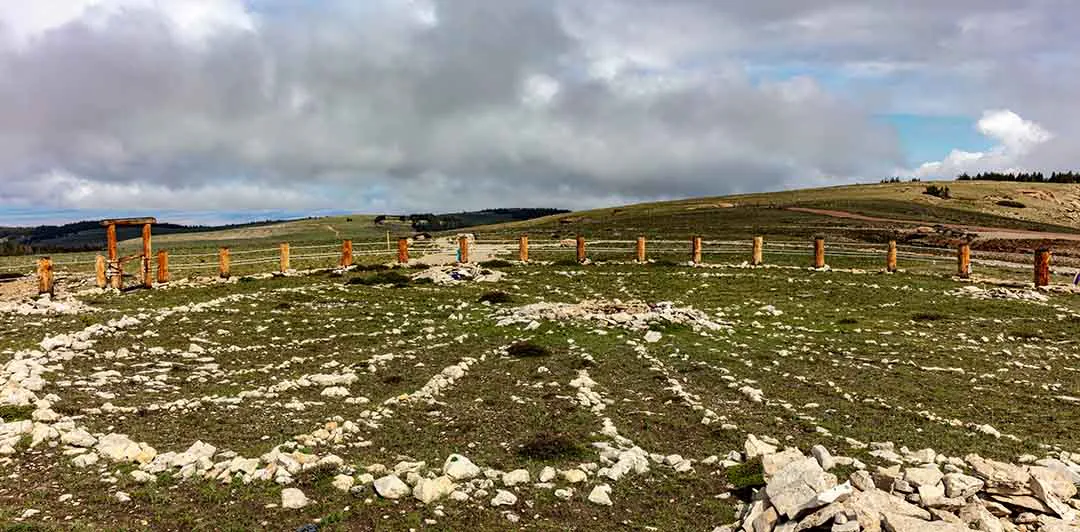 原课程讲首照片：草地上的石砌基址与木柱围栏
